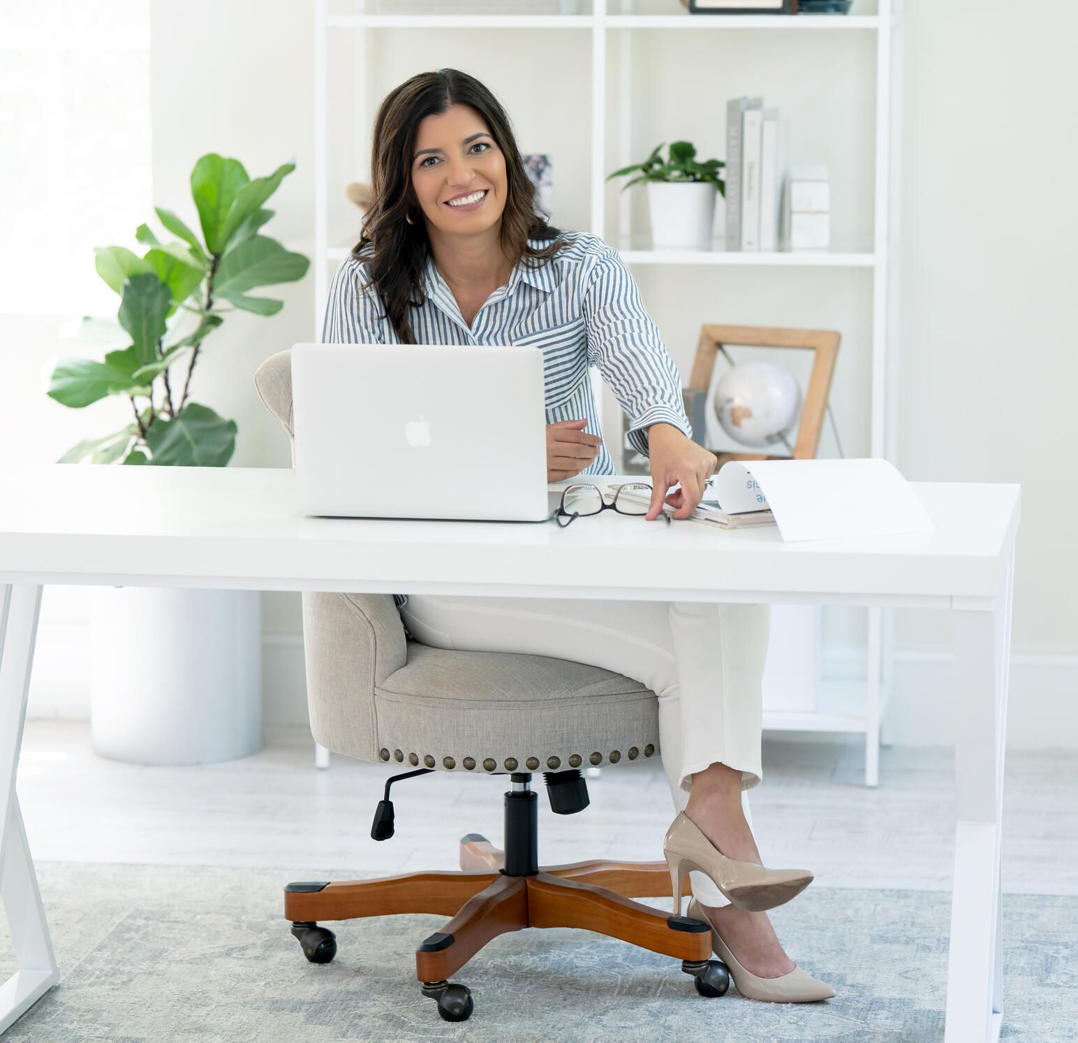 Marika Kyranos Needham Marika Needham, licensed Realtor serving Massachusetts and Rhode Island, seated at her desk in a bright office, smiling toward the camera.